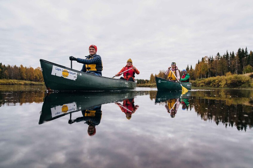 Three people canoeing on a calm river with reflections visible on the water. 5