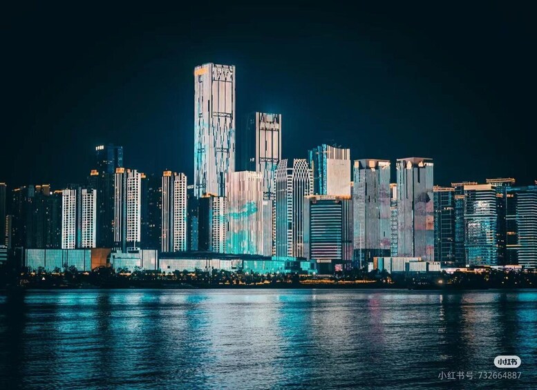 A nighttime city skyline with illuminated buildings reflecting on the water. 2