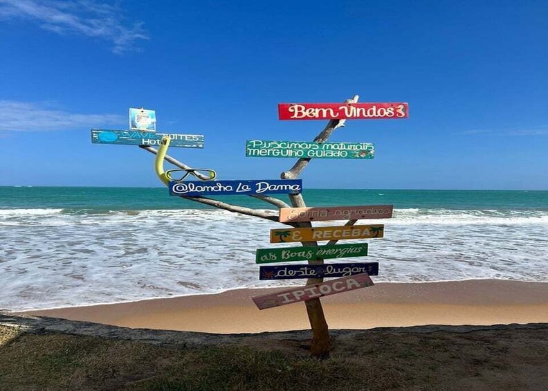 A beach with a signpost with multiple directional signs. 1