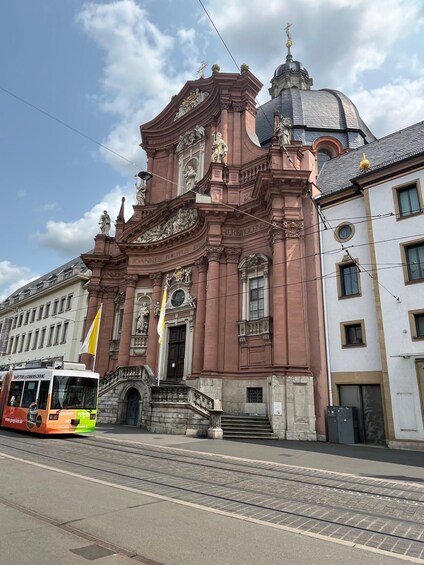 A historic building with ornate architecture, including statues and columns, and a tram passing by. 2