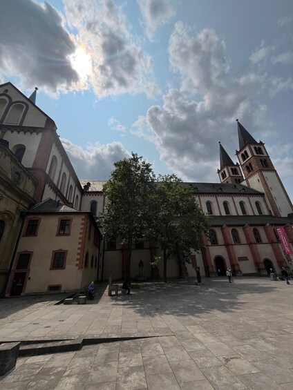 A historic building with a prominent tower and a large tree in the courtyard. 4