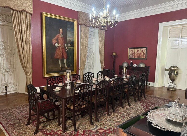 Una sala da pranzo formale con un grande quadro, poltrone decorate, un lampadario e decorazioni tradizionali. 3