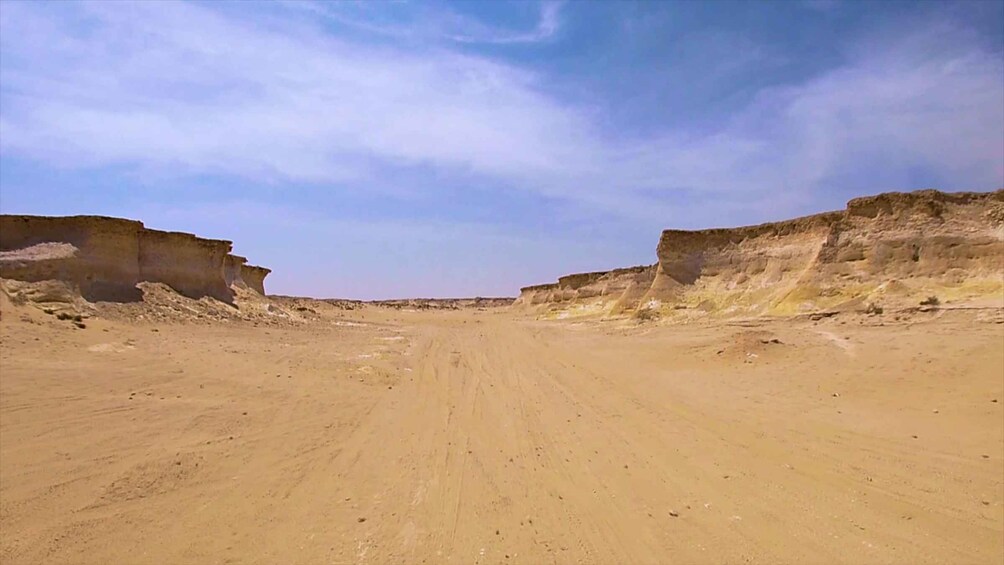 A desert landscape with a dirt road leading towards a distant horizon. 5