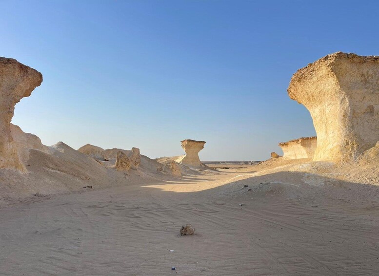 A desert landscape with prominent rock formations and a clear sky. 3