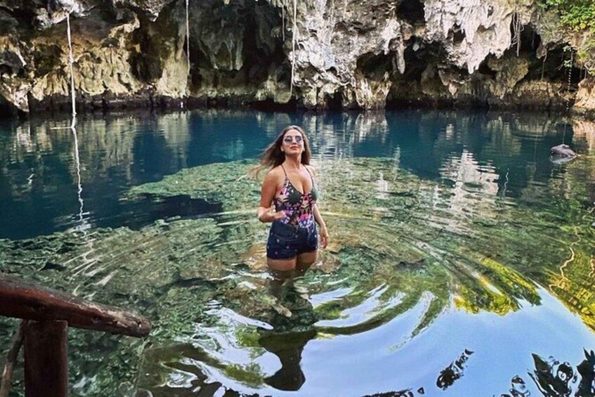 A woman standing in clear water with rocky cliffs in the background. 5