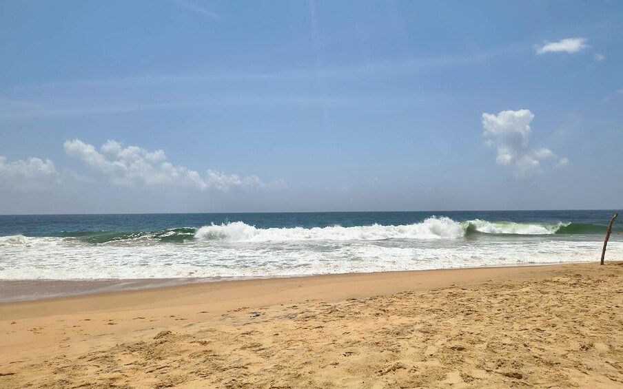 A sandy beach with waves crashing onto the shore under a clear sky. 4