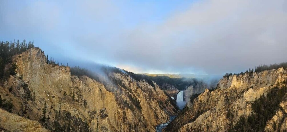A canyon with a waterfall, steep cliffs, and a forested valley. 2