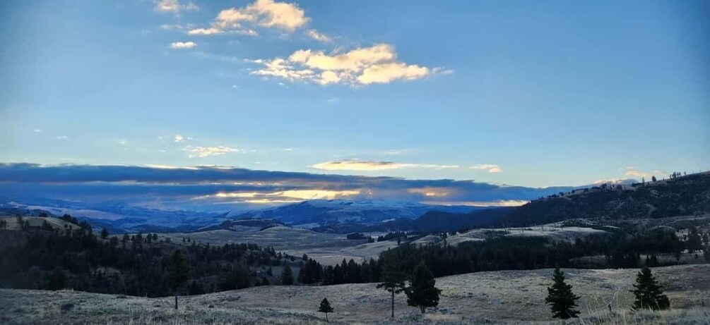 A mountainous landscape with snow-capped peaks, a clear sky, and a few scattered trees. 3