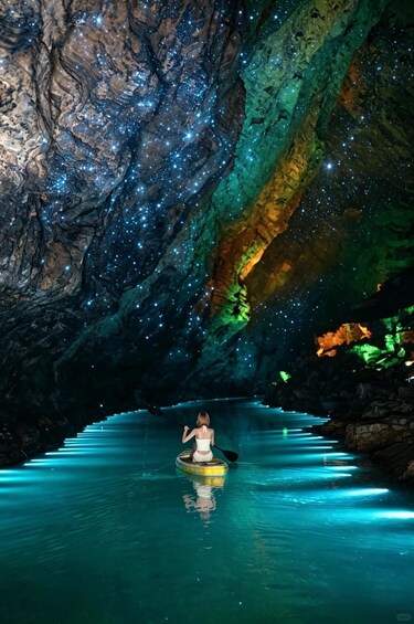 A person kayaking in a starry cave with illuminated water. 1