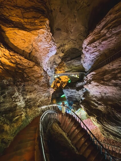 A cave with a spiral staircase and a person standing on it. 2