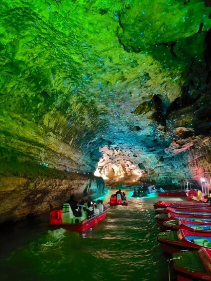 A cave with green lighting and boats on the water. 3