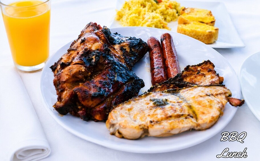 A plate of grilled meats, sausages, and a glass of orange juice. 5
