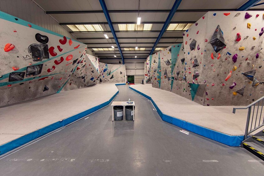 An indoor rock climbing facility with multiple climbing walls and a central walkway. 3