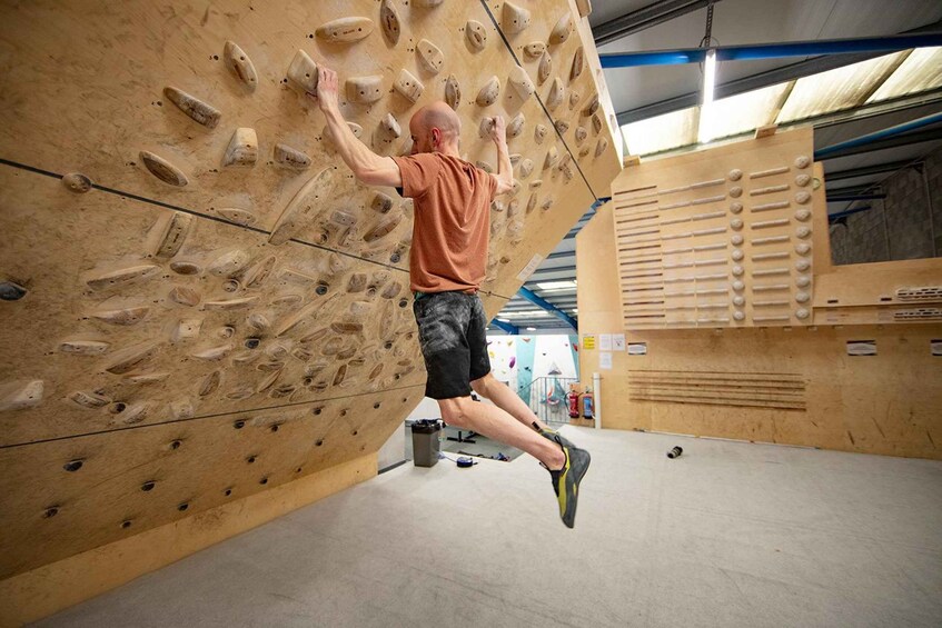 A person climbing a wooden indoor rock wall. 5