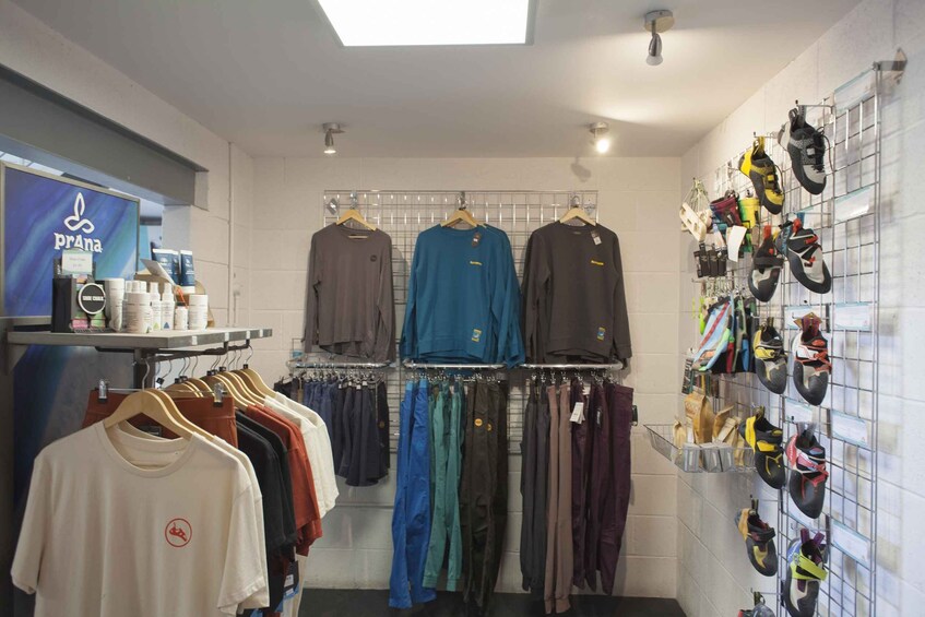 A clothing store with racks of shirts and pants, and a wall displaying various shoes. 4
