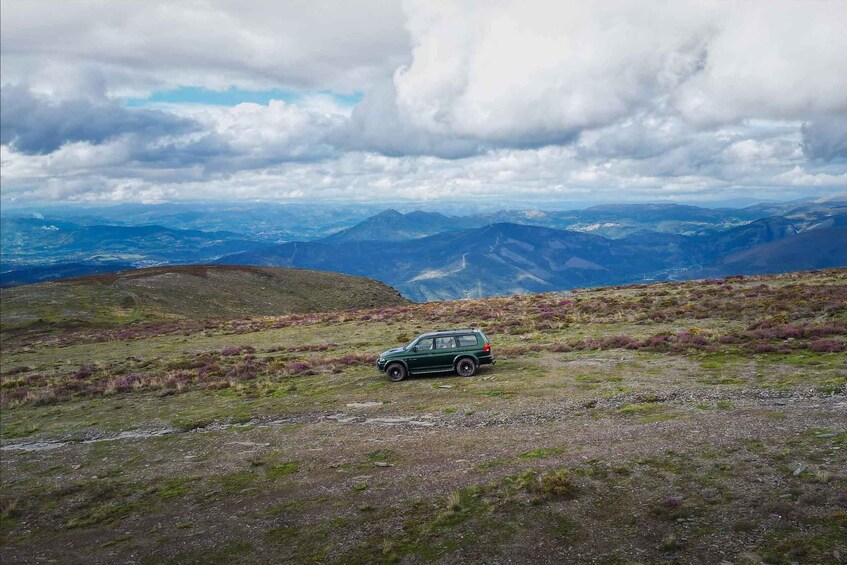 A green car parked on a grassy hill with a mountainous landscape in the background. 4