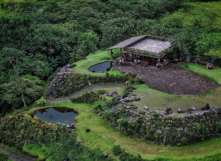 A lush garden with a wooden structure, a pond, and a stone wall. 3