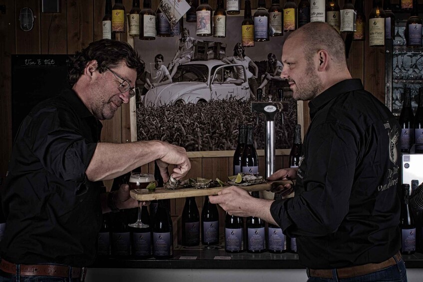 Two men serving oysters with wine bottles in a bar. 1