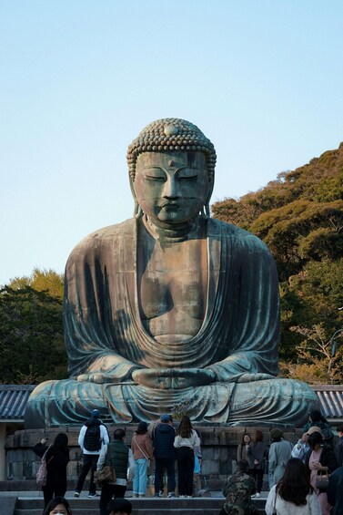 A large seated Buddha statue surrounded by visitors. 1