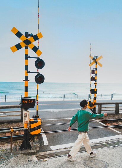 A person crossing a railway track at a level crossing with a beach in the background. 5