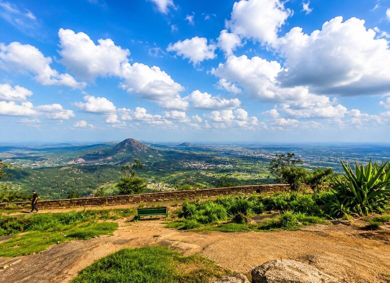 A scenic overlook with a mountain, lush greenery, and a clear blue sky. 5