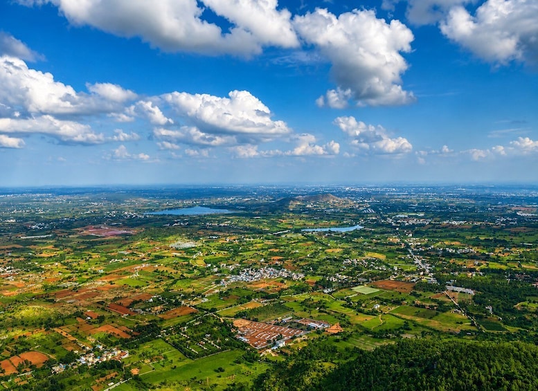 A panoramic view of a rural landscape with fields, scattered buildings, and a large body of water in the distance. 1