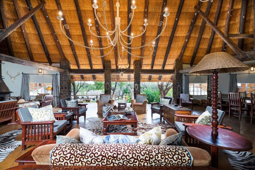 A spacious, rustic interior with a thatched roof, wooden furniture, and a chandelier. 4