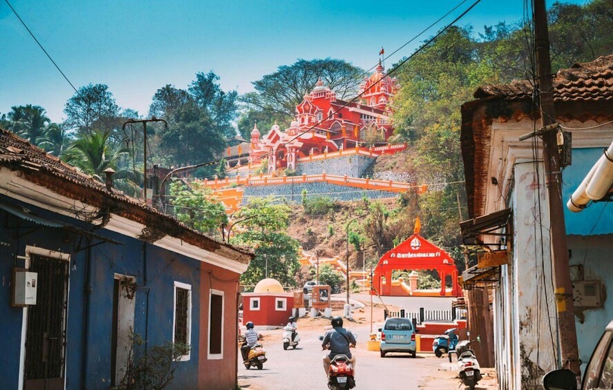 A street leading to a temple with a red roof, surrounded by residential buildings and vegetation. 2
