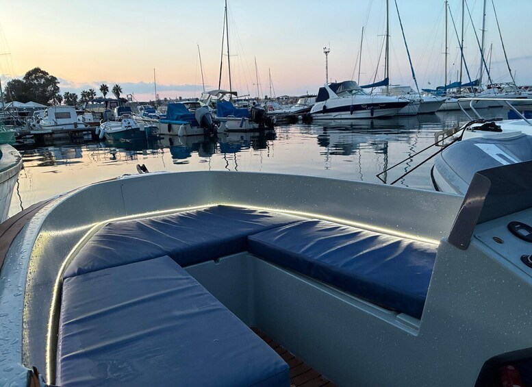 A marina with boats docked, a boat's interior with blue cushions, and a calm water surface reflecting the boats. 3