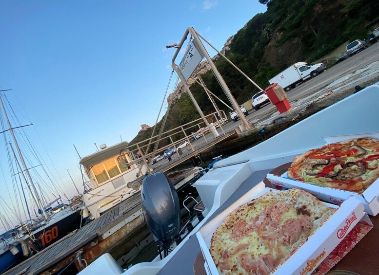 A boat docked at a marina with pizza boxes in the foreground. 1