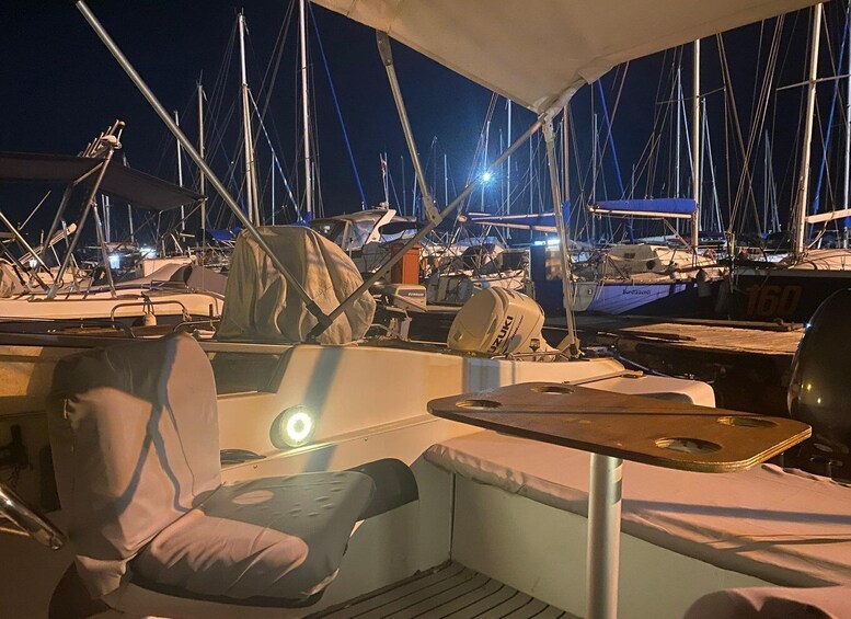 A boat deck at night with multiple sailboats docked in the background. 4