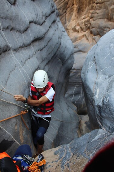 A person rappelling down a rocky cliff. 2