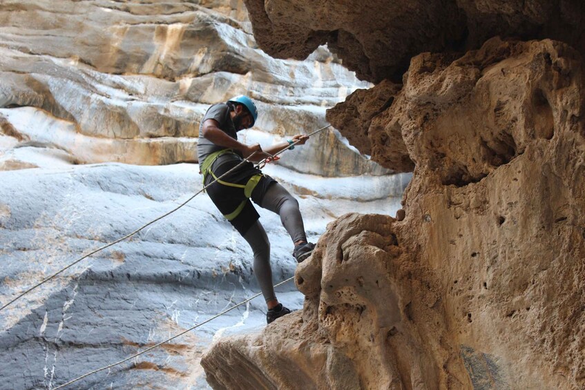 A person rappelling down a rocky cliff. 5
