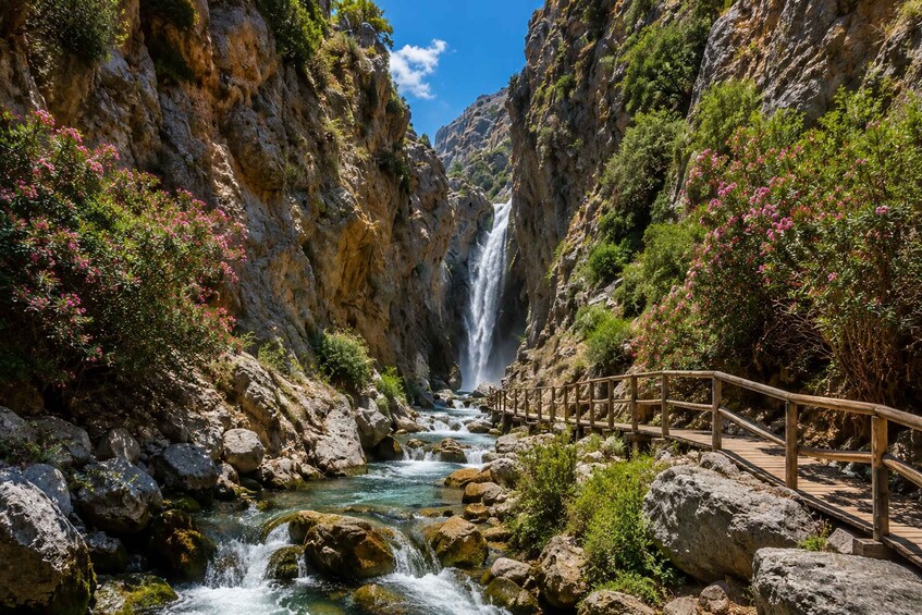 A waterfall cascading down a rocky gorge with a wooden bridge. 3