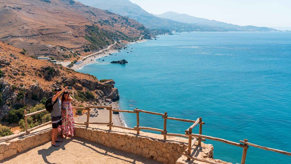 A coastal landscape with a wooden railing, rocky terrain, and a clear blue sea. 5