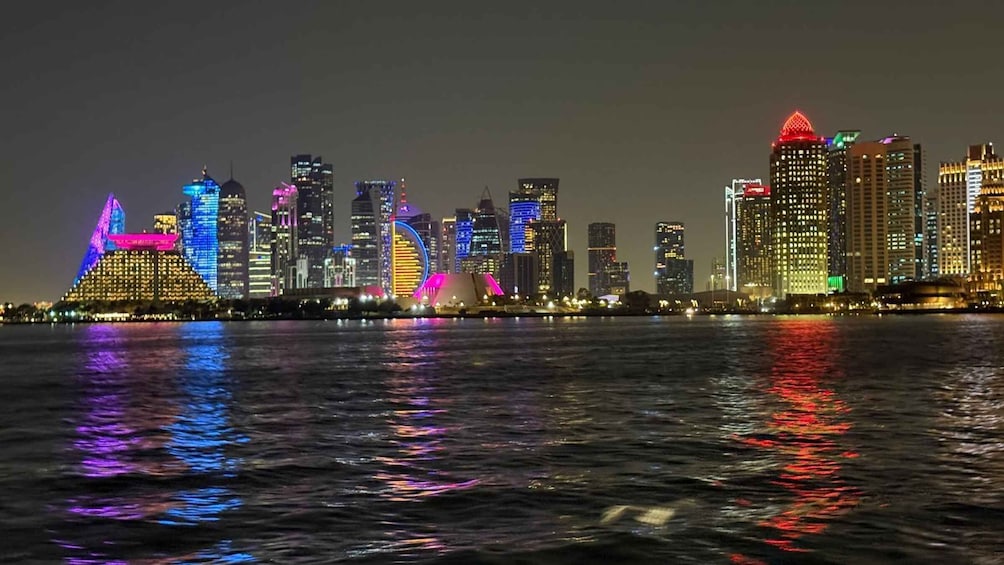 A city skyline at night with illuminated buildings reflecting on the water. 2