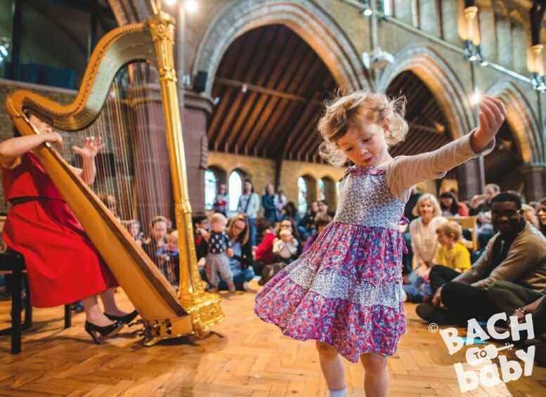 A young girl playing a harp in a church with an audience. 3