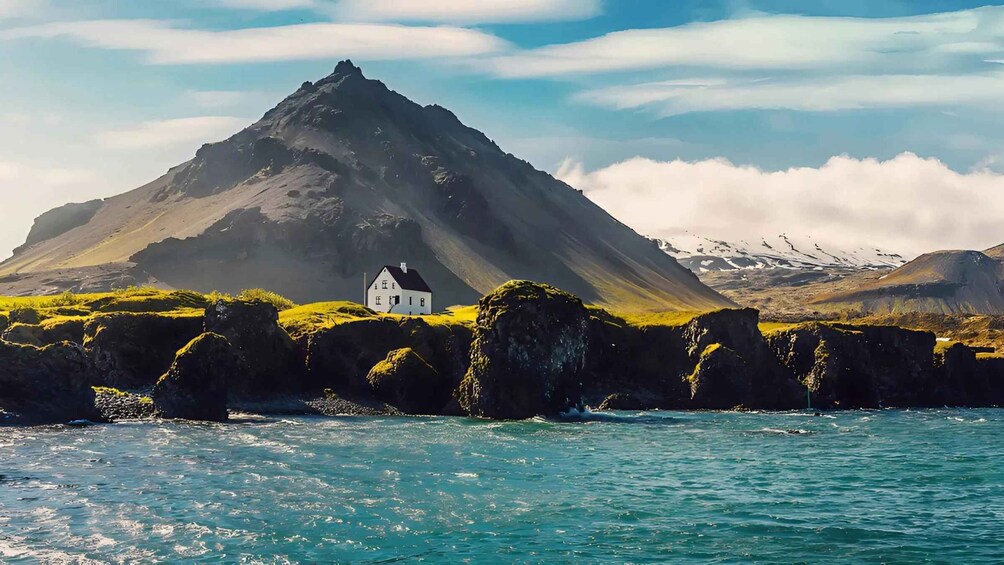 A white house on a grassy hill with a mountain in the background. 5