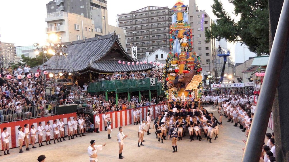 A traditional festival with a large, colorful float, spectators, and performers in traditional attire. 3