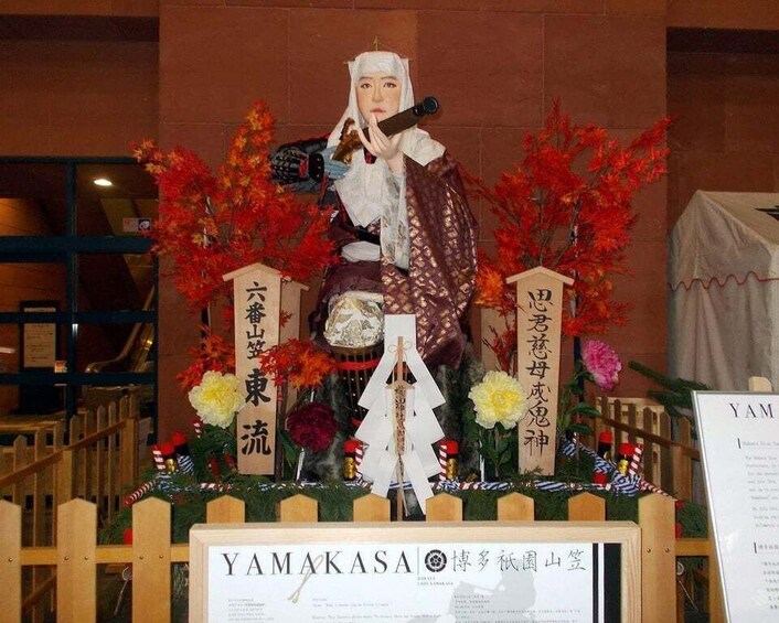 A shrine with a statue, surrounded by autumn leaves and flowers. 1