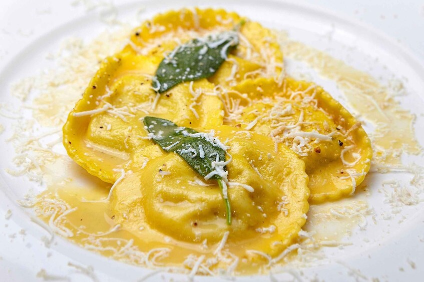 Ravioli served with a creamy sauce and grated cheese, garnished with a green herb. 2