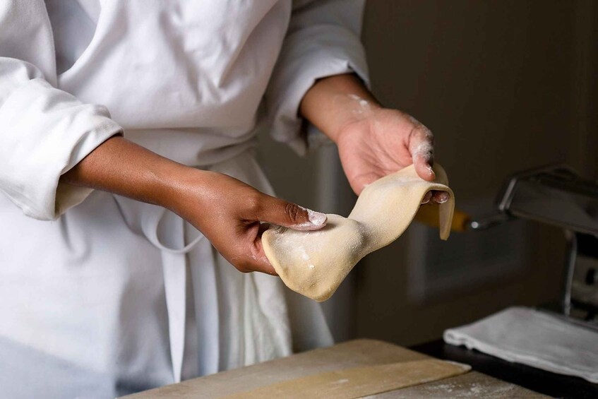 A person in a white chef's coat holding a rolled pastry. 5