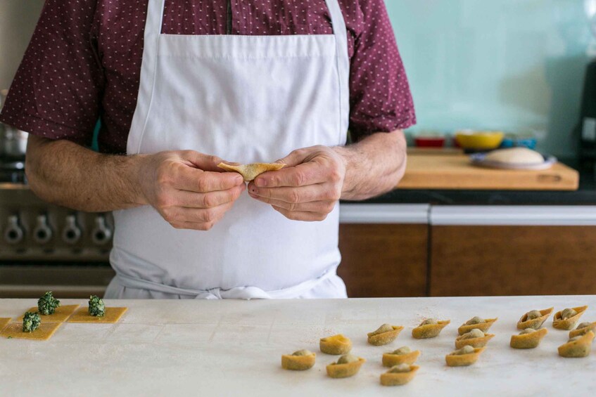 A person in a kitchen preparing food, with dough pieces on a counter. 1