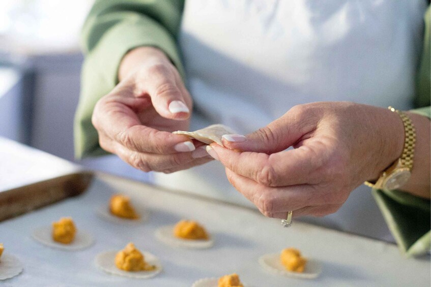 Hands holding a small object, possibly food, with a tray of similar items in the background. 4