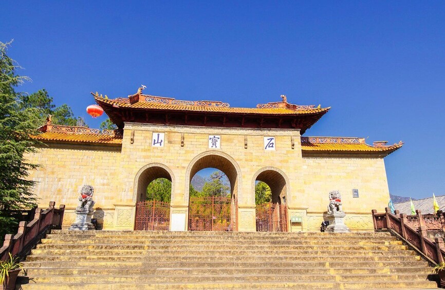 A traditional Chinese gate with three arches, a lion statue on each side, and a red lantern above. 3