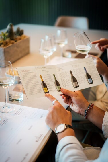 A person holding a wine bottle and a menu at a restaurant. 4