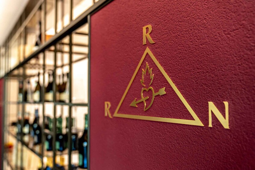 A red wall with a gold logo consisting of the letters 'R', a triangle, and 'N'. 5