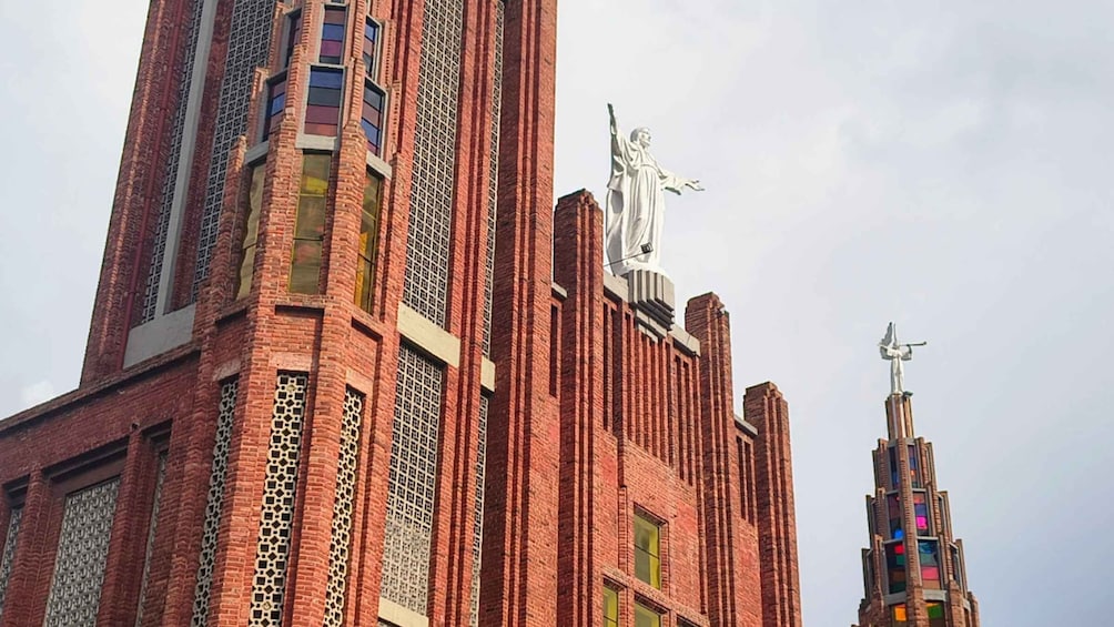 A large brick building with a statue on top and a smaller statue on the side. 1