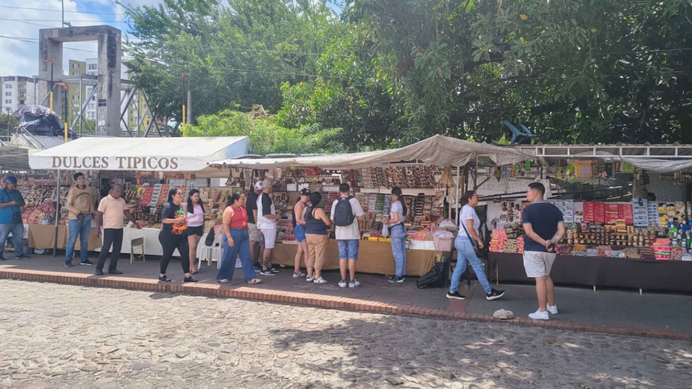 A street market with people shopping and vendors selling goods. 2