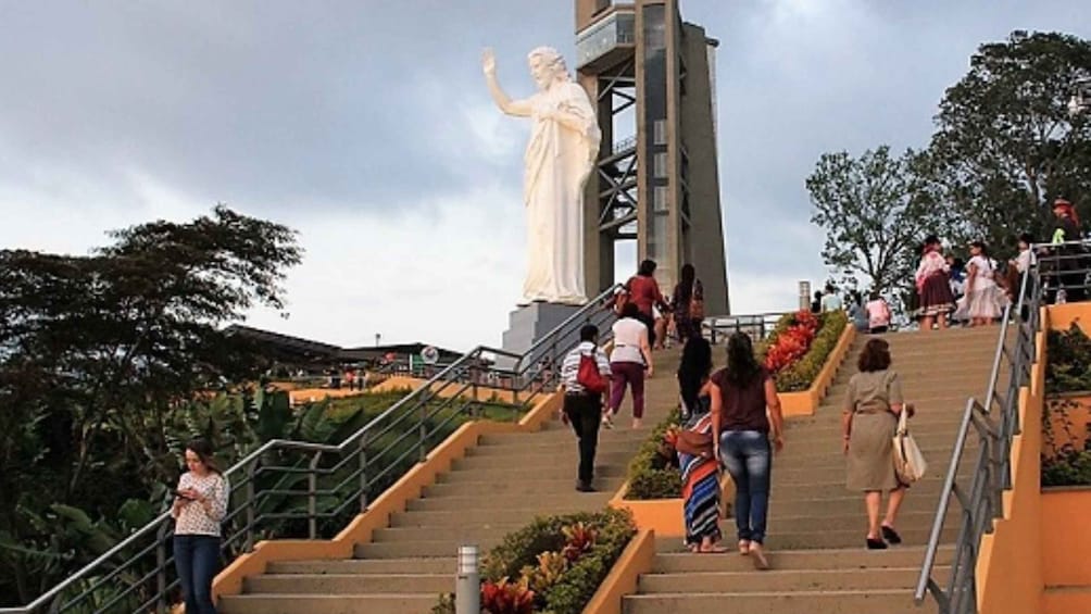A large white statue on a tall pedestal, surrounded by stairs and greenery. 4